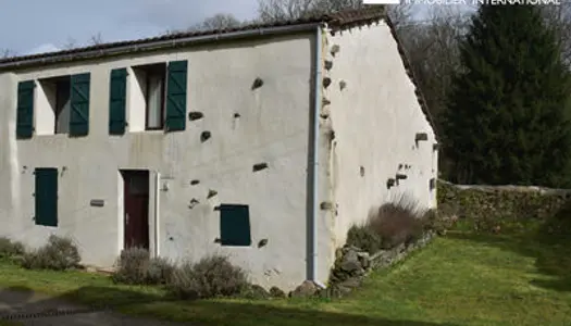 Grange en pierre convertie en maison dans un cadre bucolique en bord de rivière.